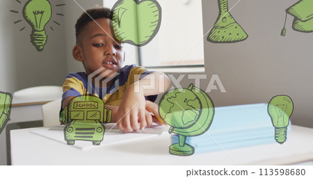 Image of green school icons over happy african american schoolboy working at desk in class Image of green school icons over happy african american schoolboy working at desk in class 113598680