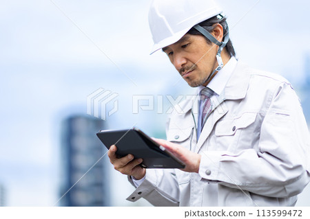 Man looking at blueprints on tablet 113599472