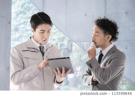 People in work clothes having a meeting looking at a tablet, businessmen who are presidents or managers, IT and DX 113599648