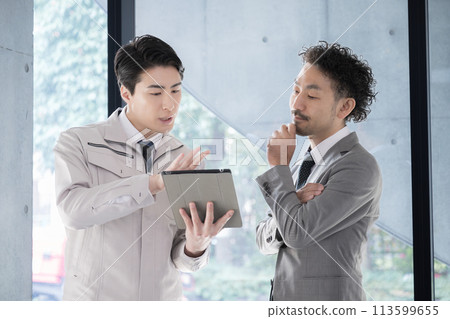 People in work clothes having a meeting looking at a tablet, businessmen who are presidents or managers, IT and DX 113599655
