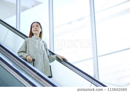 Female inbound foreign tourist walking down the escalator with a suitcase Female inbound foreign tourist walking down the escalator with a suitcase 113602089
