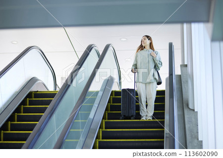 Female inbound foreign tourist walking down the escalator with a suitcase Female inbound foreign tourist walking down the escalator with a suitcase 113602090