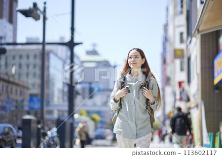 Female foreign tourist walking through the city with a backpack Female foreign tourist walking through the city with a backpack 113602117