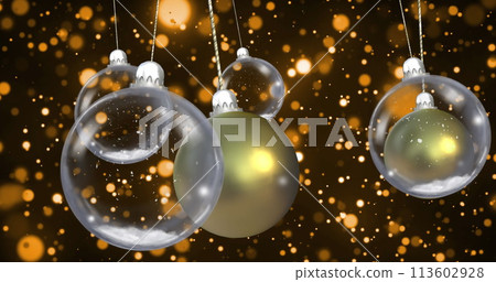 Image of christmas baubles dangling with snow falling on black background 113602928