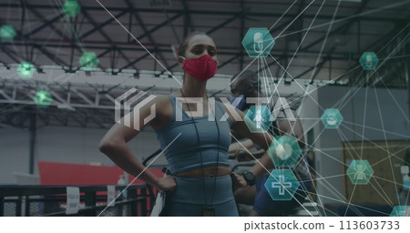Globe of medical icons spinning against female fitness trainer wearing face mask standing in the gym Globe of medical icons spinning against female fitness trainer wearing face mask standing in the gym 113603733