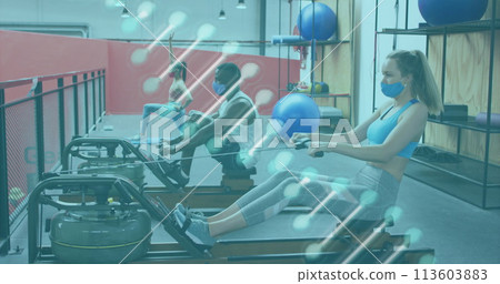 Dna structure spinning against caucasian woman wearing face mask performing rowing exercise at gym Dna structure spinning against caucasian woman wearing face mask performing rowing exercise at gym 113603883