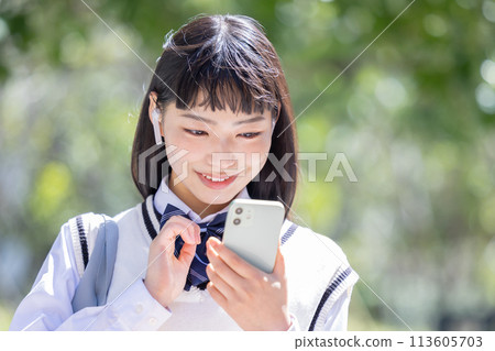 戴著耳機看著智慧型手機的高中女孩 戴著耳機看著智慧型手機的高中女孩 113605703