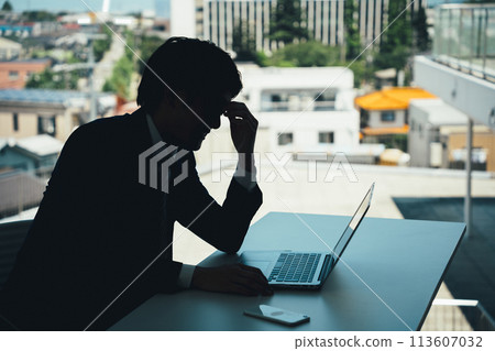 Silhouette of a male businessman working at a desk suffering from eye strain, dry eyes, tired eyes, and blurred vision Silhouette of a male businessman working at a desk suffering from eye strain, dry eyes, tired eyes, and blurred vision 113607032
