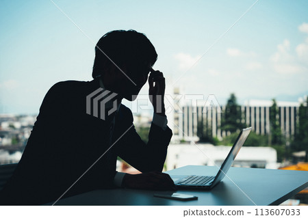Silhouette of a businessman doing desk work (headache, tired eyes, trouble, stress, shock, mistake) 113607033