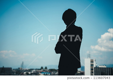 Silhouette of a young male businessman in a suit with his arms folded in the office (worried, thinking, serious) 113607043