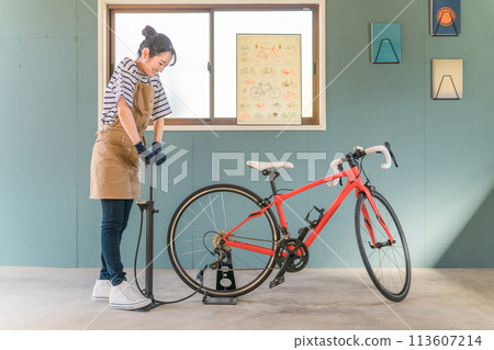 Young Asian woman inflating road bike tires in her garage at home Young Asian woman inflating road bike tires in her garage at home 113607214