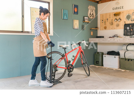 年輕的亞洲女性在家車庫裡為公路自行車輪胎充氣 113607215