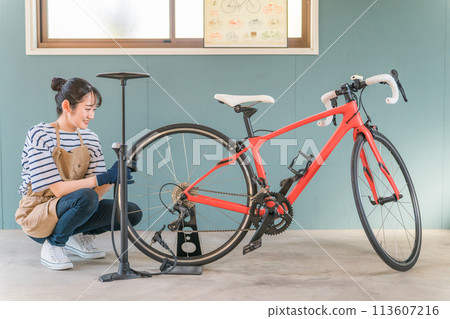 Young Asian woman inflating road bike tires in her garage at home 113607216