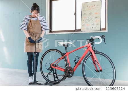 Young Asian woman inflating road bike tires in her garage at home Young Asian woman inflating road bike tires in her garage at home 113607224