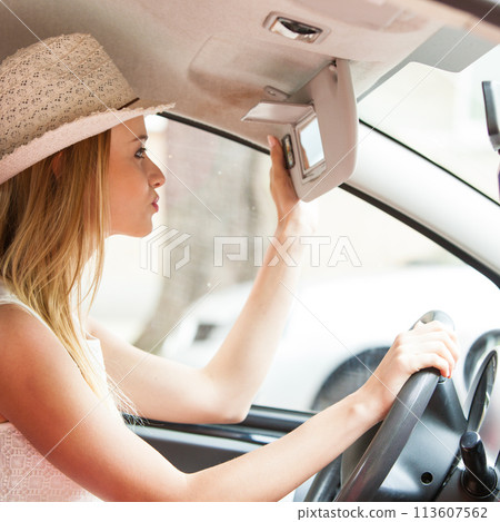 Distracted woman driving her car looking in mirror 113607562