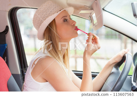 Woman applying makeup while driving her car Woman applying makeup while driving her car 113607563
