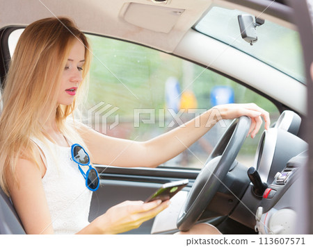 Woman using phone while driving her car Woman using phone while driving her car 113607571