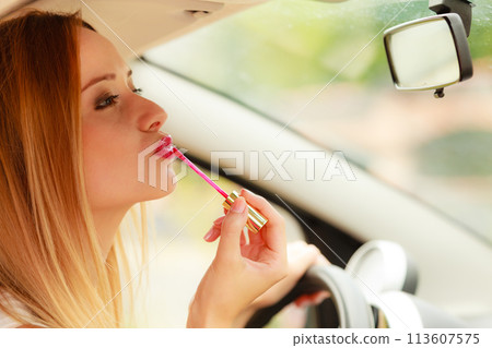 Woman applying makeup while driving her car 113607575