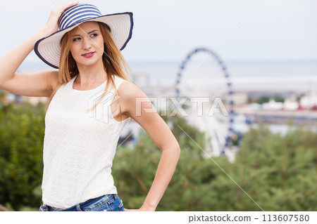 Attractive woman wearing sun hat and white top 113607580