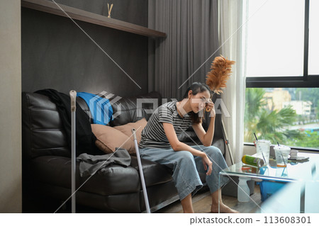 Young housewife sitting on sofa with cleaning tools feeling tired after doing housework 113608301