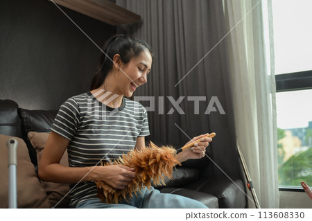 Cheerful young housewife singing, having fun while cleaning house Cheerful young housewife singing, having fun while cleaning house 113608330