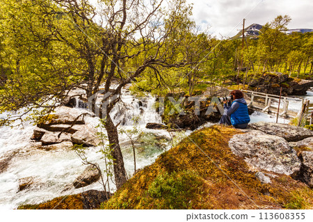 Tourist with camera at river, Norway 113608355
