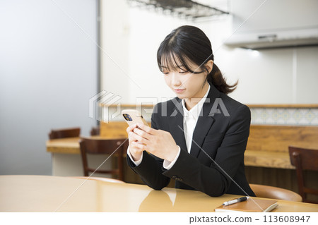 A young woman in a business suit using a smartphone in a cafe A young woman in a business suit using a smartphone in a cafe 113608947