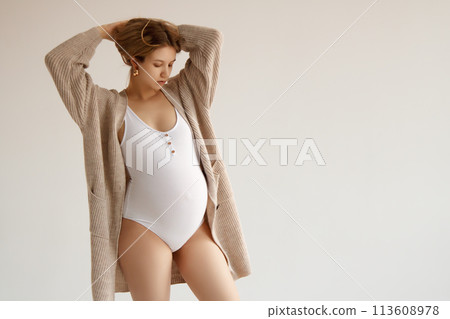 A beautiful pregnant girl in a white bodysuit and 113608978