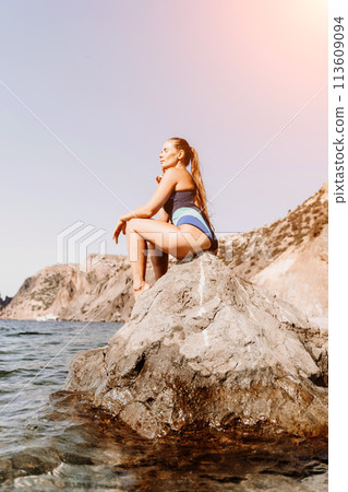 Woman travel summer sea. A happy tourist in a blue bikini enjoying the scenic view of the sea and volcanic mountains while taking pictures to capture the memories of her travel adventure. Woman travel summer sea. A happy tourist in a blue bikini enjoying the scenic view of the sea and volcanic mountains while taking pictures to capture the memories of her travel adventure. 113609094