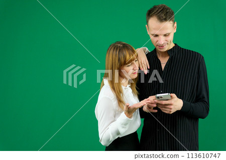 man and woman with gadgets tablet phone in hands on green background talking laugh in office holding meeting learning to work on Internet flirting relationships flirting. couple solving issue 113610747