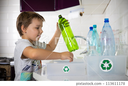 A boy enthusiastically puts plastic bottles into boxes separately from caps for recycling. Sorting plastic waste for recycling. The boy cares about preserving nature by sending plastic for recycling. A boy enthusiastically puts plastic bottles into boxes separately from caps for recycling. Sorting plastic waste for recycling. The boy cares about preserving nature by sending plastic for recycling. 113611178