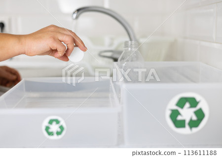 Zero waste Sorting plastic. A woman cleans plastic bottles under water and places them in a recycling bin. Conscious use of plastic and sending it for recycling. Saving the planet from plastic waste. 113611188