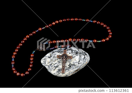 Crucifix and Rosary Beads on a Granite Rock on a Black Background Crucifix and Rosary Beads on a Granite Rock on a Black Background 113612361