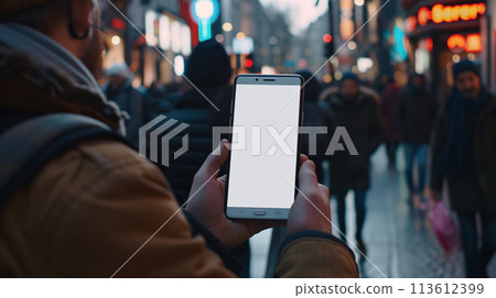 a curious tourist stands clutching a smartphone with a blank, white screen in a foreign city  a curious tourist stands clutching a smartphone with a blank, white screen in a foreign city  113612399