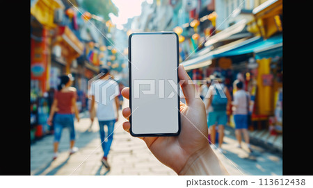 a curious tourist stands clutching a smartphone with a blank, white screen in a foreign city  113612438