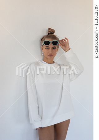 Beautiful blonde girl in a hoodie and panties posing with her back on a white background Beautiful blonde girl in a hoodie and panties posing with her back on a white background 113612507