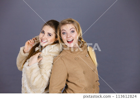 Two women wearing light brown coats Two women wearing light brown coats 113612824