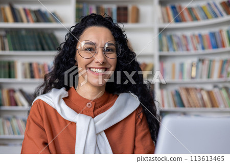 An image of a young adult in casual attire, deeply focused while studying in a library, surrounded by books. An image of a young adult in casual attire, deeply focused while studying in a library, surrounded by books. 113613465