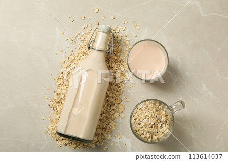 Bottle and glass with milk, oatmeal on beige background, top view Bottle and glass with milk, oatmeal on beige background, top view 113614037