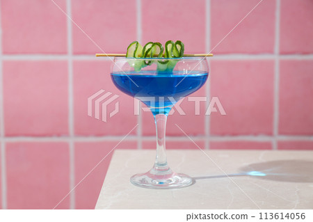 Blue cocktail with cucumber slice in glass on pink background, close up 113614056