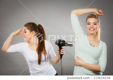Woman drying friend armpit with hair dryer Woman drying friend armpit with hair dryer 113614236