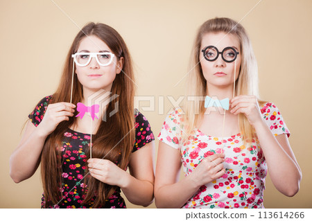 Two serious women holding carnival accessoies on stick Two serious women holding carnival accessoies on stick 113614266