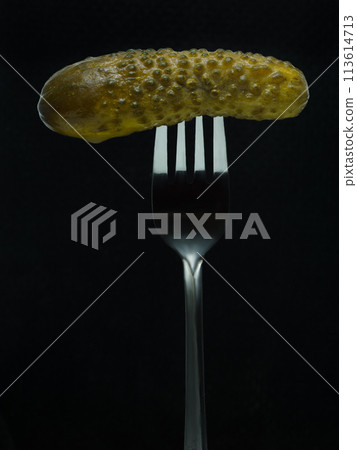 pickle on a fork shot on a black background. Vertical orientation pickle on a fork shot on a black background. Vertical orientation 113614713