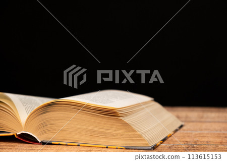 Open book on wooden and black background. The wisdom of generations, knowledge and love of reading, a place for text. 113615153