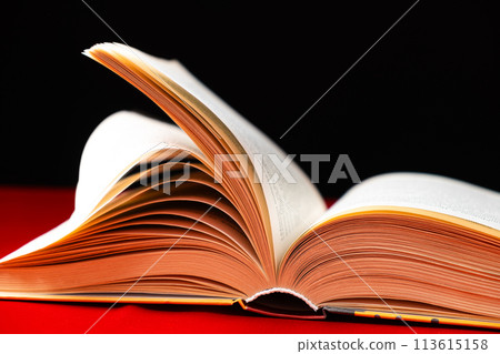 Pages of a thick book are turned on a red and black background. 113615158