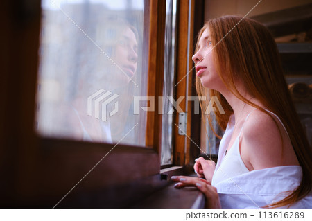 Young redhead Woman in white shirt Looks Out The Window on the balcony Deep In Thought red hairs ginger girl general plane Young redhead Woman in white shirt Looks Out The Window on the balcony Deep In Thought red hairs ginger girl general plane 113616289