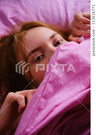 Young redhead Teenager Girl with blue eyes and red hairs Relaxing On pink Bed At Home closing her nose with pink sheet playing peekaboo Young redhead Teenager Girl with blue eyes and red hairs Relaxing On pink Bed At Home closing her nose with pink sheet playing peekaboo 113616771