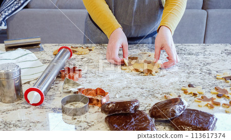 Using various festive cookie cutters, we're cutting out charming gingerbread cookies from the rolled dough on the sleek marble counter, bringing holiday cheer to the modern kitchen. Using various festive cookie cutters, we're cutting out charming gingerbread cookies from the rolled dough on the sleek marble counter, bringing holiday cheer to the modern kitchen. 113617374