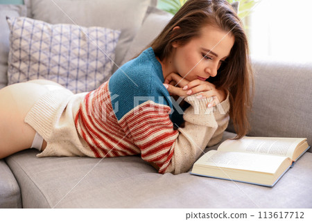 Ypung woman reading a book on the couch Ypung woman reading a book on the couch 113617712