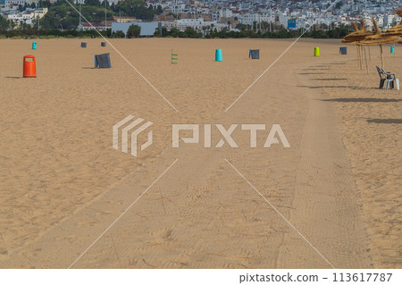 Sandy resort city beach, with tracks of a tractor that has just passed, which collects garbage from surface of sand. Infrastructure and works to maintain the performance of tourist recreation areas Sandy resort city beach, with tracks of a tractor that has just passed, which collects garbage from surface of sand. Infrastructure and works to maintain the performance of tourist recreation areas 113617787